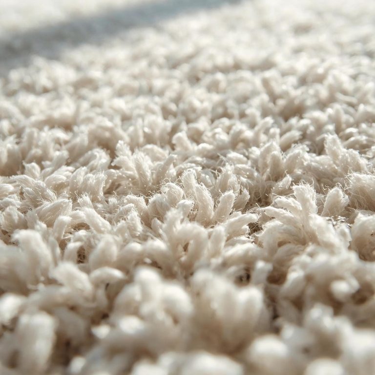 Three professional cleaners in green and red overalls working in a modern kitchen, mopping the floor, and cleaning high walls and windows.